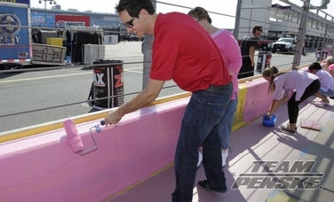 Joey Logano paints the CMS pit wall pink in October.